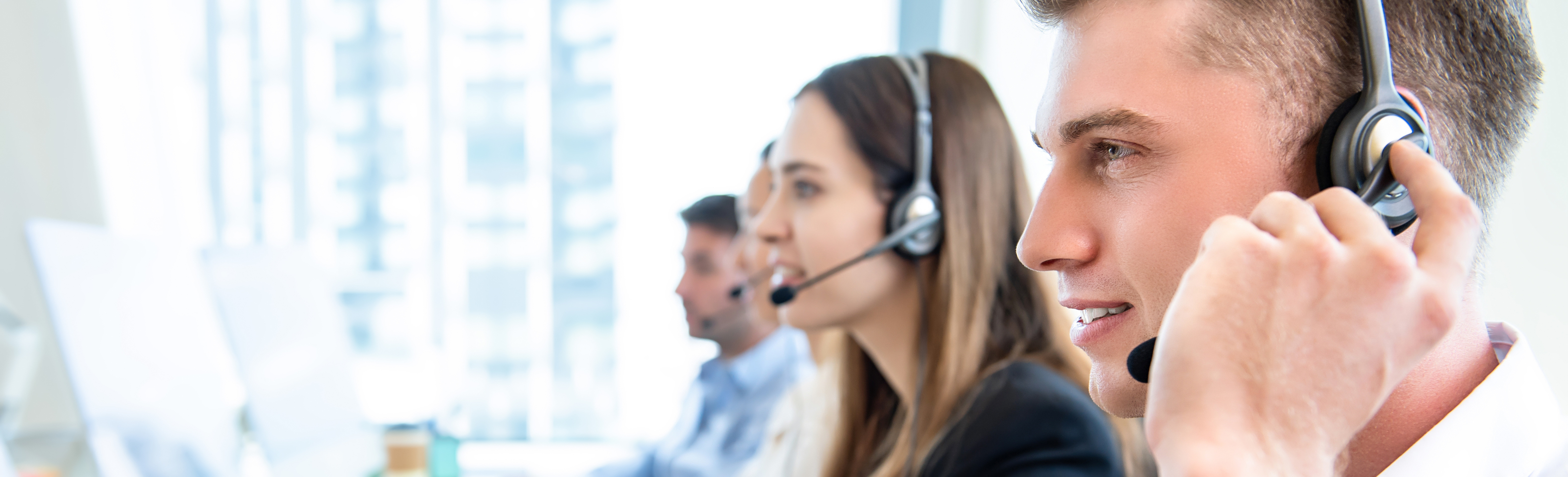 Male operator staff with team talking to customers in call center office, panoramic web banner with copy space